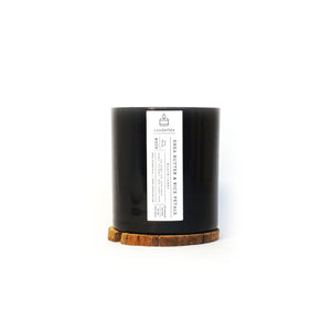 Soy Candle in Shea Butter & Rice Petals scent in a sleek black tumbler featuring a minimalist white label and displayed on a wooden coaster