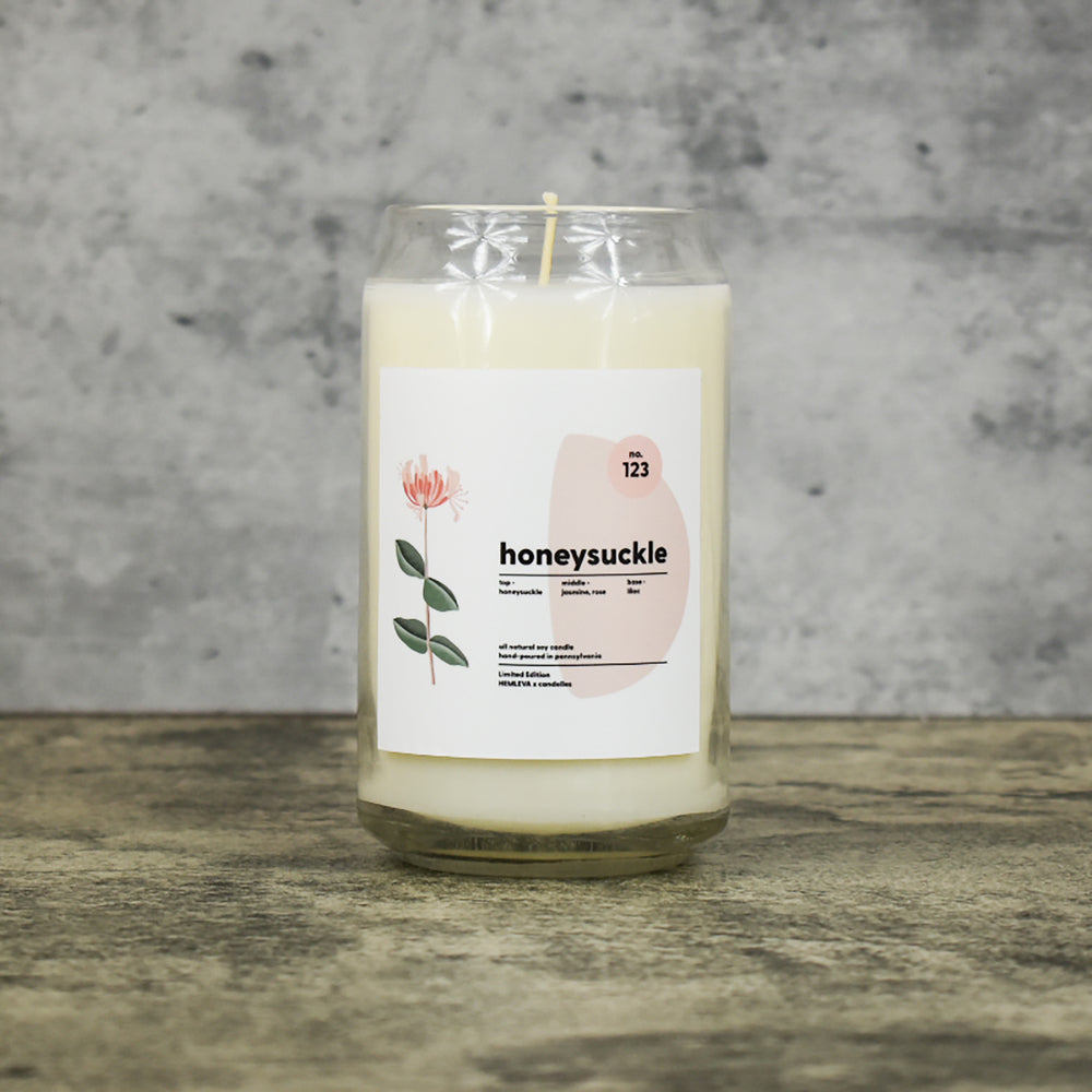 Honeysuckle scent soy wax candle in can shaped glass vessel with tapered top and beautifully minimal label with pastel shapes and a floral drawing from our Hemleva Collaboration
