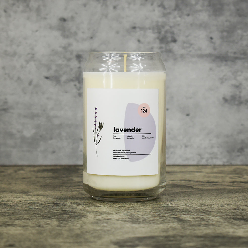 Lavender scent soy wax candle in can shaped glass vessel with tapered top and beautifully minimal label with pastel shapes and a floral drawing from our Hemleva Collaboration